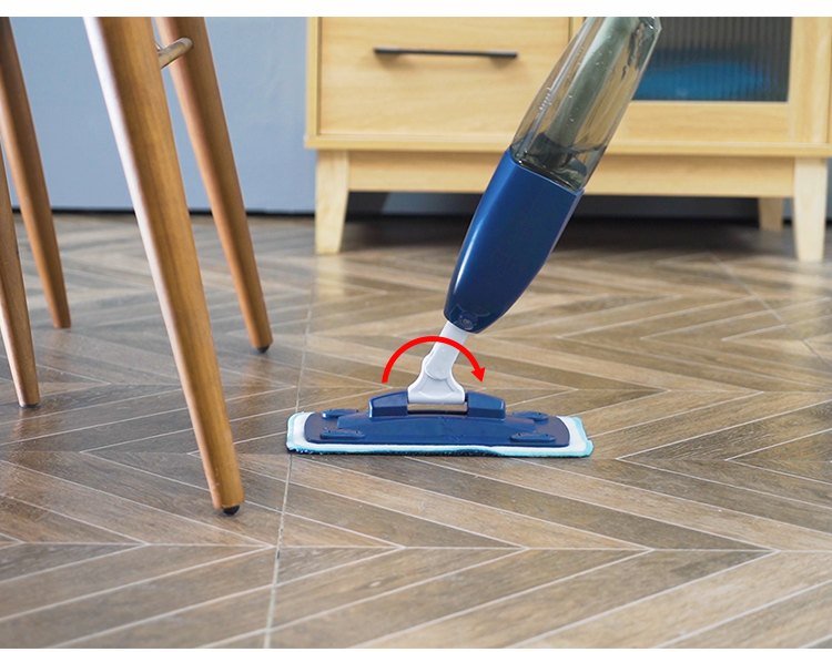 Navy spray mop head swivelling on a herringbone floor beside chair legs
