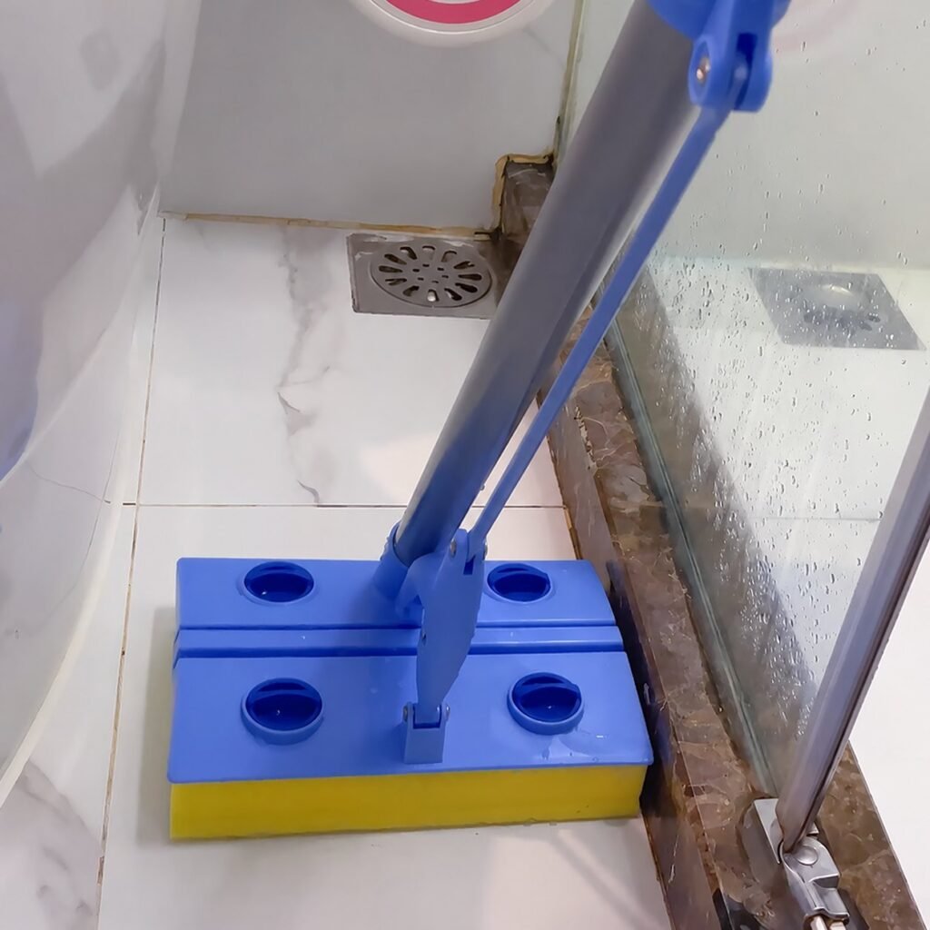 Cellulose sponge mop head in a bathroom corner beside a shower screen and drain