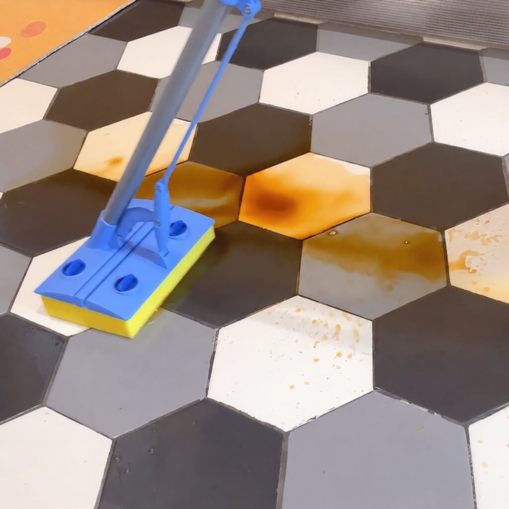 Cellulose sponge mop wiping a brown spill off hexagonal floor tiles