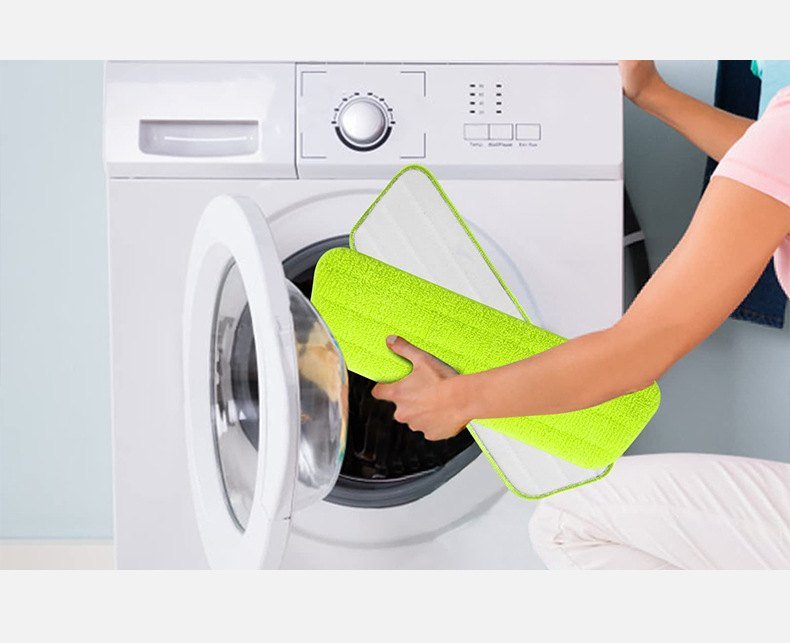 Green microfiber mop pad being put into a front-loading washing machine