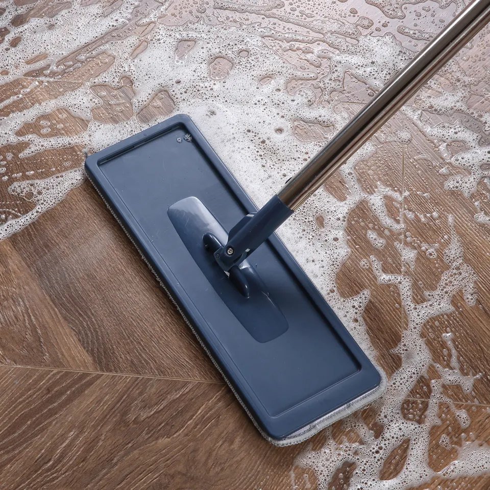 Blue flat mop head on a swivel joint mopping a soapy wooden floor