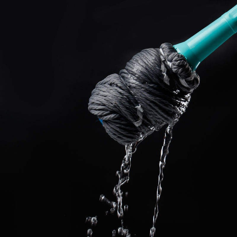 Water running out of the twisted grey microfiber head of the twist mop