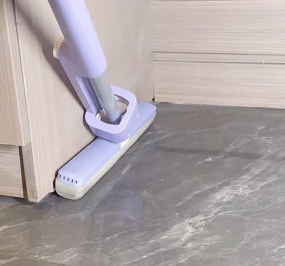 Lilac sponge mop head running along the foot of a wooden cabinet