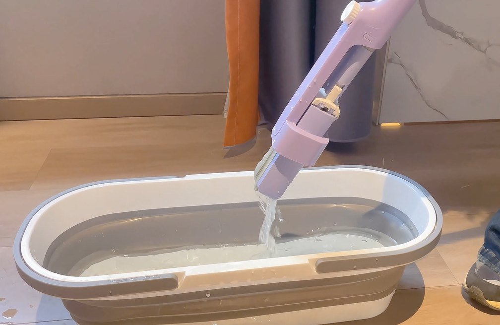 Folded sponge head wrung inside the lilac sleeve, water pouring into a basin