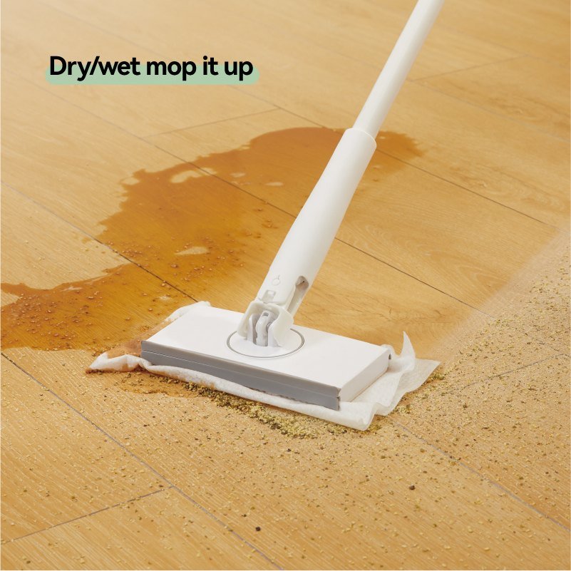 Mini clip mop with a disposable wipe cleaning a spill and debris on wood flooring