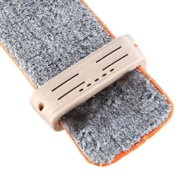 Wringing clip of the flat mop gathering hair from a grey microfiber pad