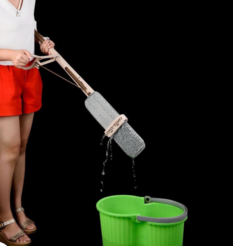 Woman pulling the handle lever to wring the flat mop pad over a green bucket