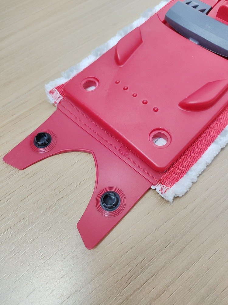 Red rubber snap tab of the microfiber pad lying beside a red flat mop plate