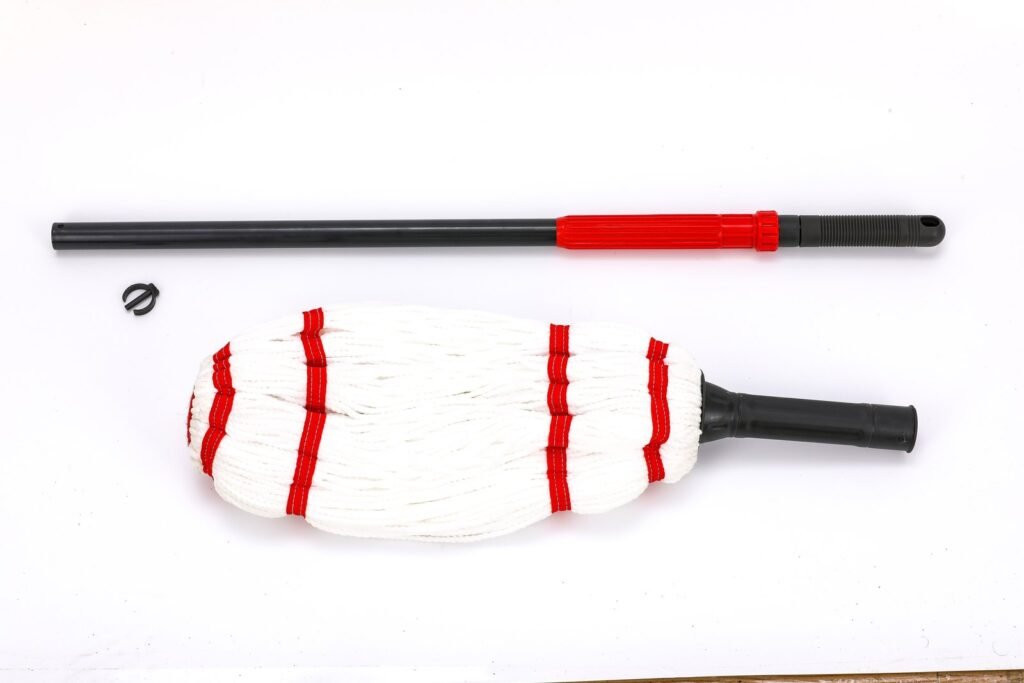Twist mop parts laid out: red and black handle, strip head with socket and clip