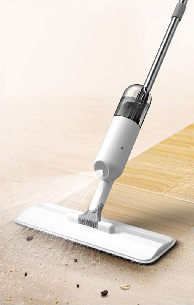 Nozzle of the white spray mop spraying a fan of water over a wooden floor